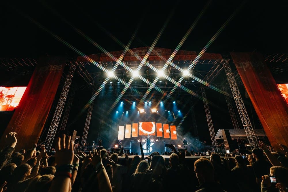 The Uprise main stage at night, star-burst lights over a crowd with their hands up